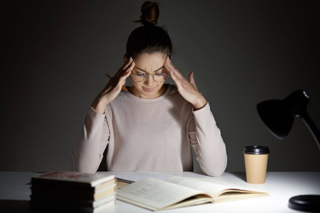 Exhausted premed student needing MCAT burnout prevention while studying late.